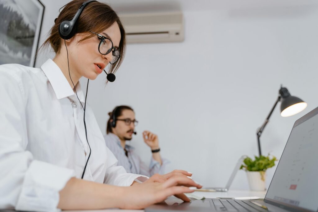 Focused customer support professionals working in a modern office with headsets and laptops.
